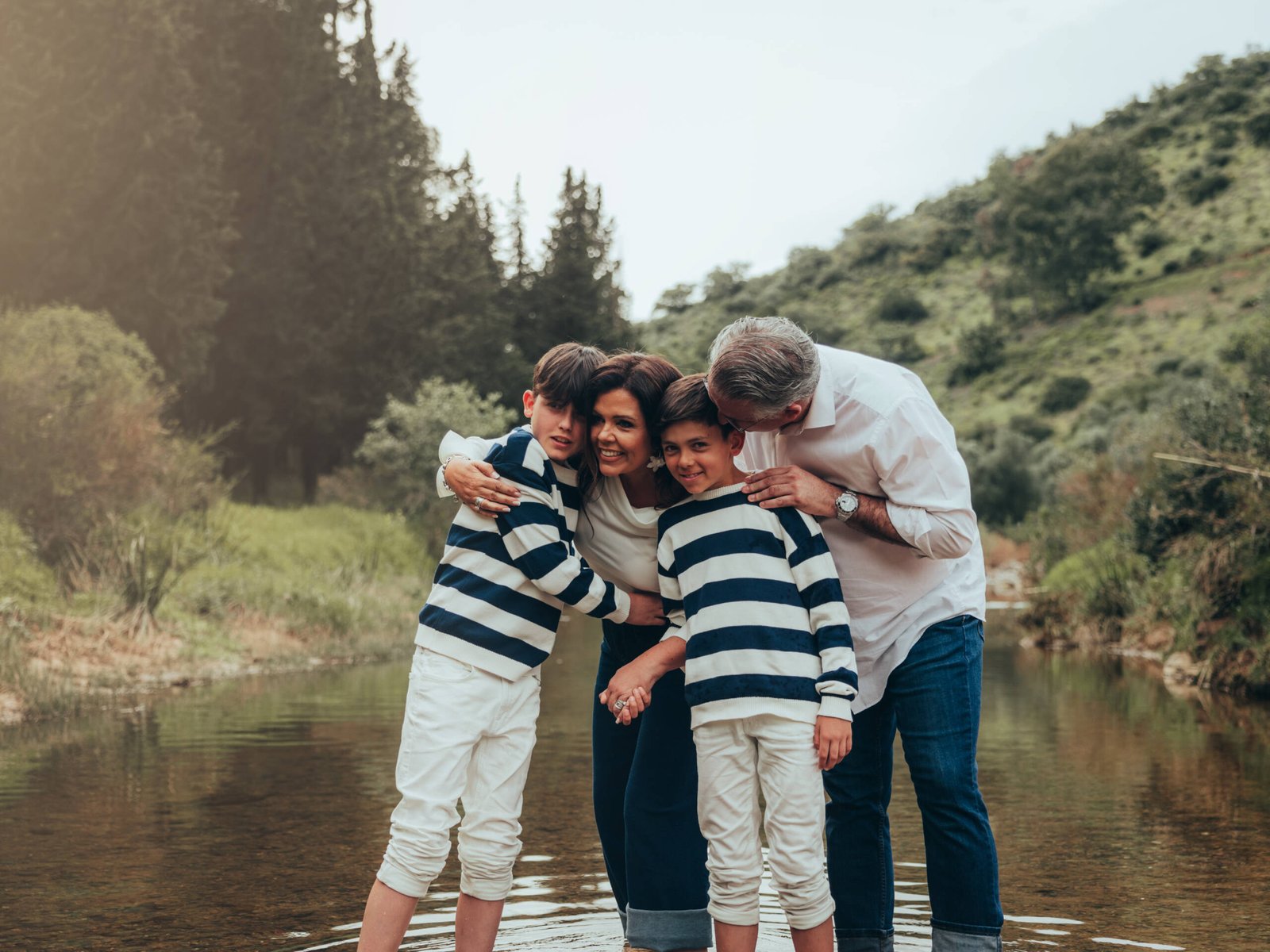Padres y dos hijos abrazados en un río durante una sesión de fotografía familiar de Garoy.